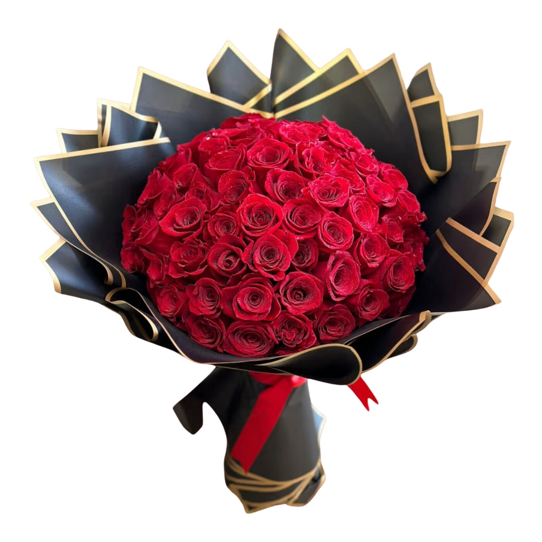 A bouquet of red roses with green leaves, arranged with a black and gold ribbon.