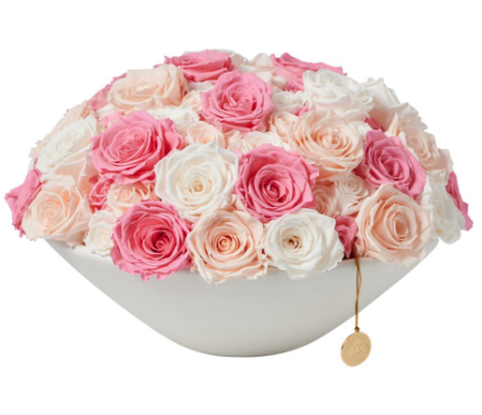 Floral arrangement of preserved roses in pastel tones with an elegant white base.