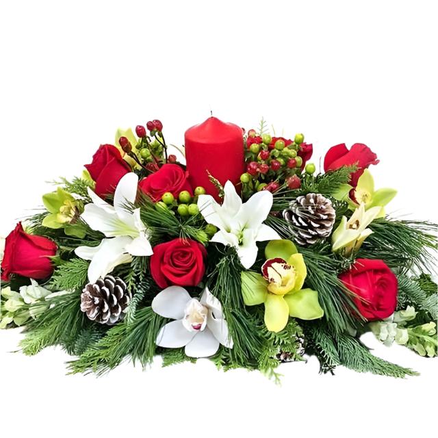 A festive Christmas table center featuring a red candle, surrounded by a variety of fresh flowers including red and white roses, green pine branches, and yellow orchids, all arranged to create a warm and celebratory display.