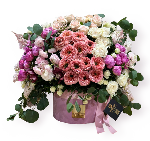 A bouquet of pink roses, peonies, and hydrangeas arranged in a pink-colored vase.