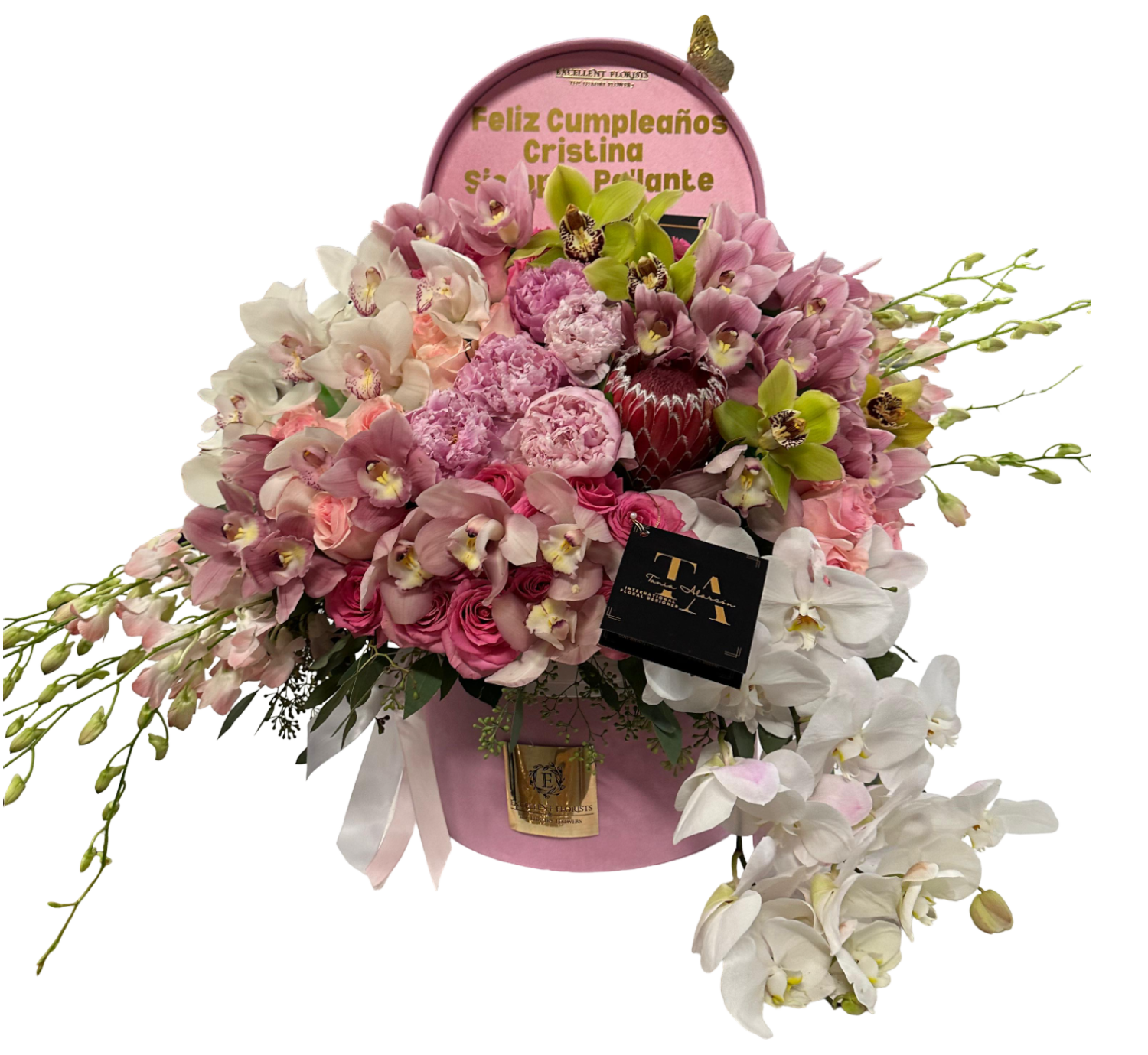 A floral arrangement featuring a variety of orchids in shades of pink, white, and green, presented in a box with a clear window and a greeting message.