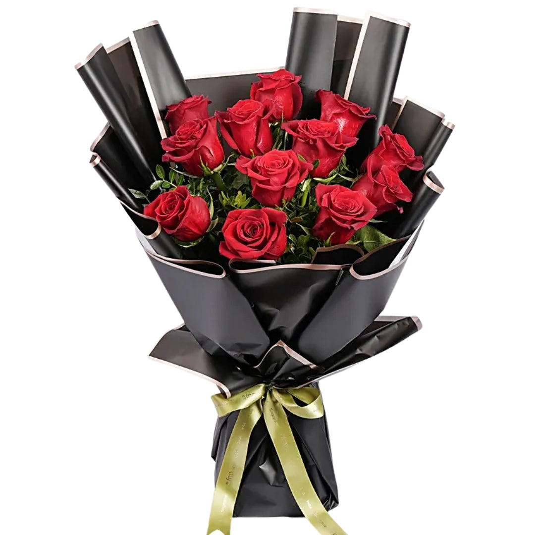 A dozen red roses arranged in a bouquet with black wrapping paper and a gold ribbon.