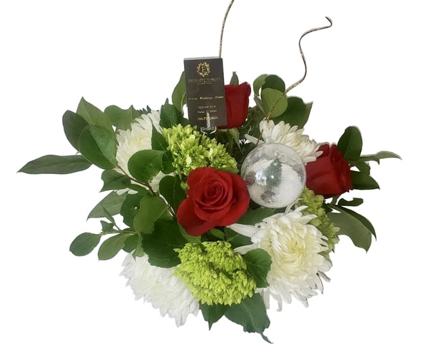 Holiday centerpiece with red roses, white spider chrysanthemums and green ornament