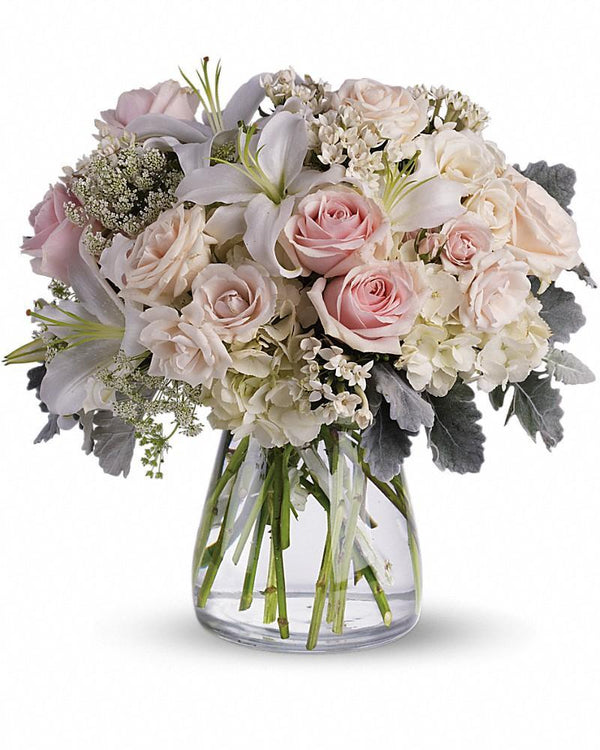 Pink and white roses and lilies floral arrangement in glass vase