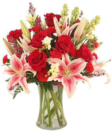 Fresh red roses and pink lilies arranged in a clear glass vase