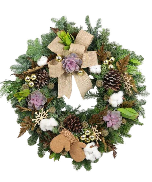 An evergreen holiday wreath decorated with red and burlap ribbon, succulents, cinnamon, pine cones, and magnolia leafs.