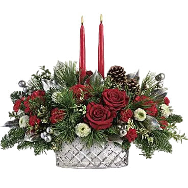 A floral holiday arrangement featuring red and white roses, green pine branches, and white hypericum, with a silver vase.